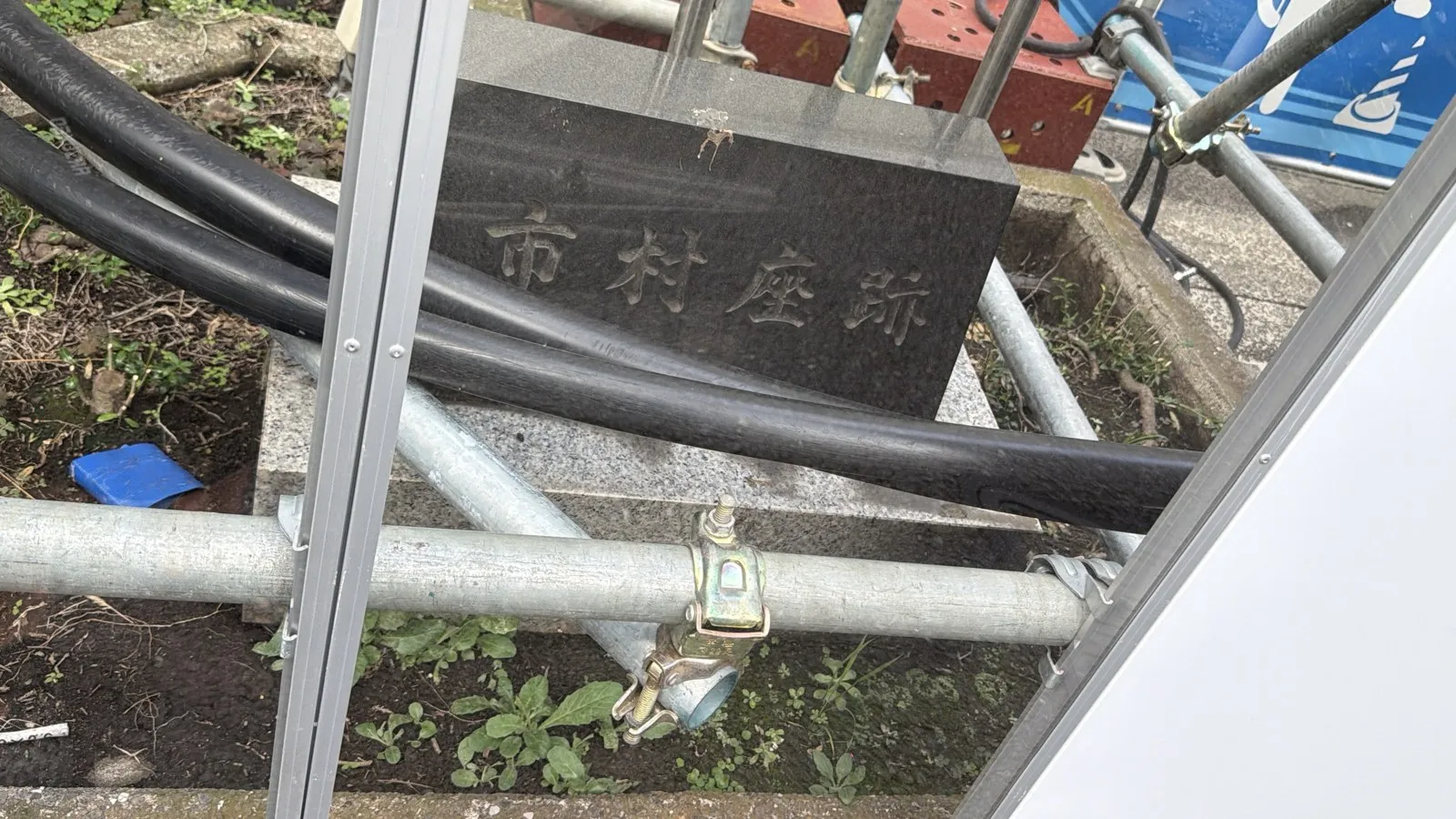 工事の囲いの透明な部分越しに見える「市村座跡」の碑