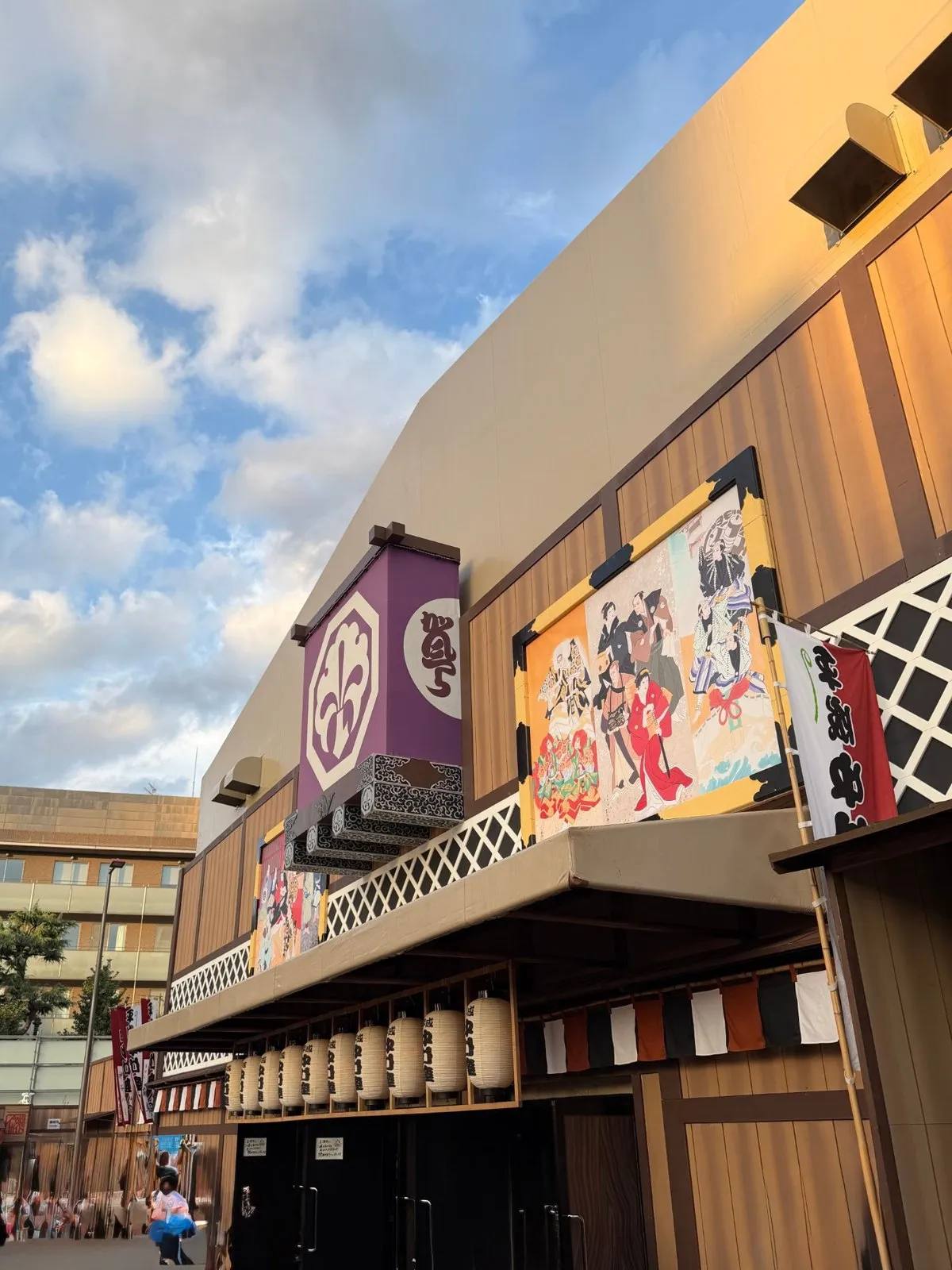 夕方の平成中村座の表。紫の櫓に座紋、その横に絵看板が掛かる